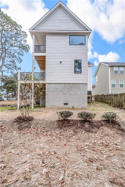 back of house with crawl space, a balcony, and fence