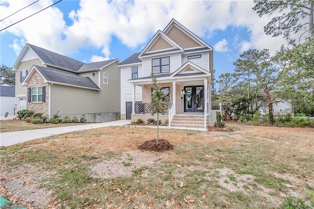 view of front of house featuring covered porch, brick siding, and french doors