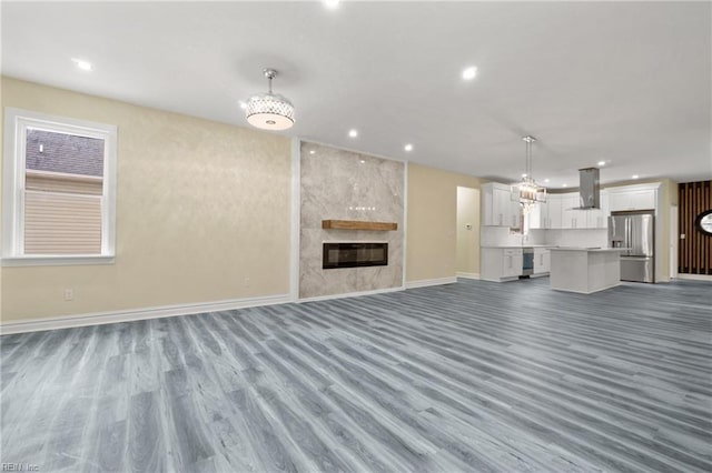 unfurnished living room featuring recessed lighting, a fireplace, baseboards, and wood finished floors