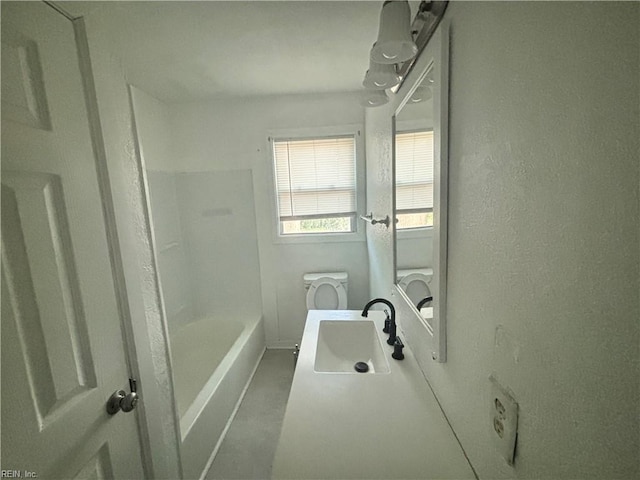 bathroom featuring a textured wall, vanity, and toilet