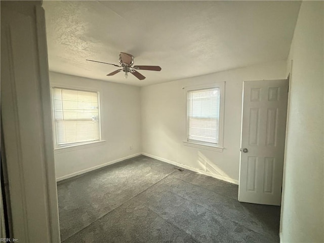 empty room with dark carpet, a textured ceiling, baseboards, and ceiling fan