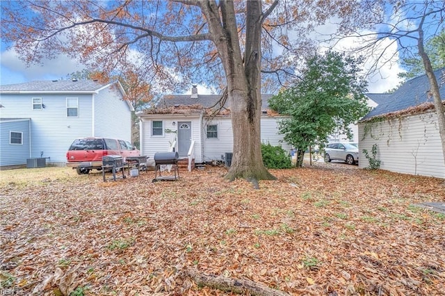 rear view of house with entry steps, central AC, and a chimney