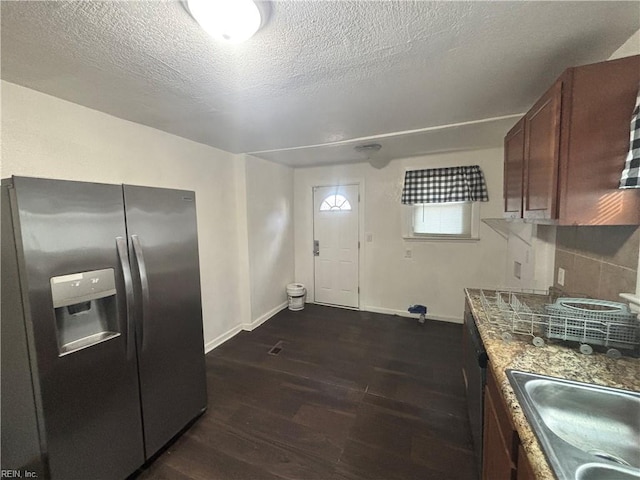 kitchen featuring a textured ceiling, dark wood-type flooring, a sink, baseboards, and stainless steel refrigerator with ice dispenser