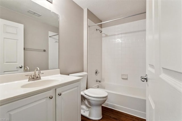 bathroom featuring visible vents, toilet, wood finished floors, tub / shower combination, and vanity