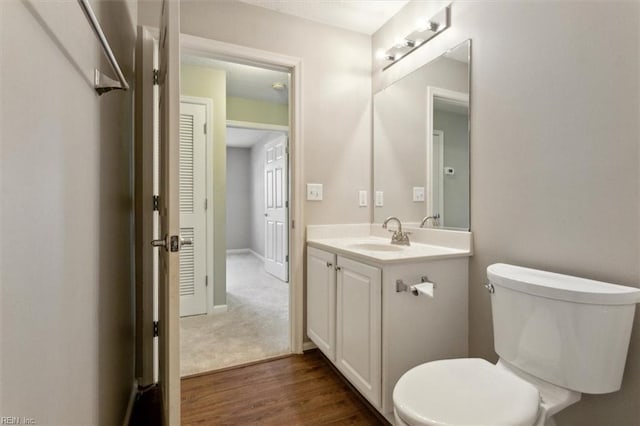 bathroom with baseboards, vanity, toilet, and wood finished floors