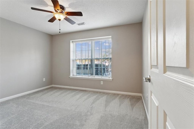 carpeted spare room with visible vents, baseboards, ceiling fan, and a textured ceiling