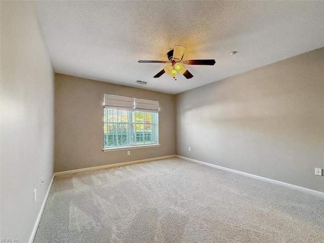 carpeted empty room with a ceiling fan, baseboards, visible vents, and a textured ceiling