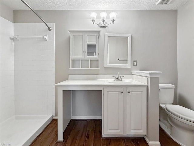 bathroom with toilet, vanity, tiled shower, and wood finished floors