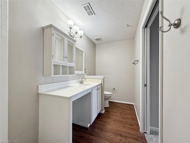 bathroom featuring toilet, a textured ceiling, vanity, and visible vents