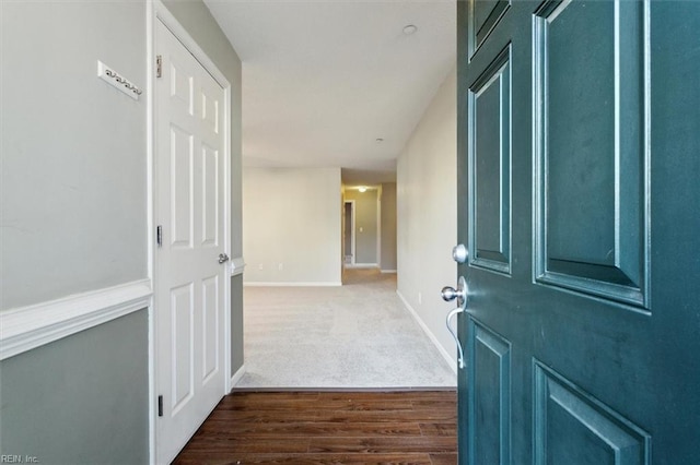 corridor with dark carpet, baseboards, and dark wood finished floors