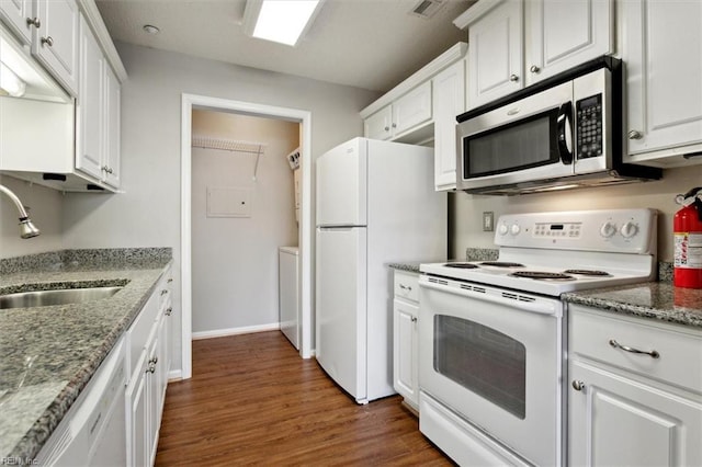 kitchen with white appliances, dark wood finished floors, stone counters, white cabinetry, and a sink