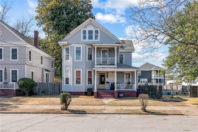 view of front of house featuring a porch, fence, and a balcony