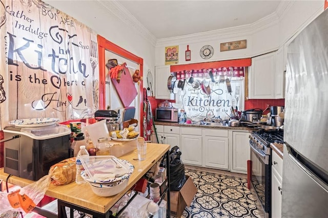 kitchen with stainless steel appliances, a sink, white cabinets, and crown molding