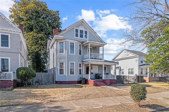 view of front facade with a chimney, a porch, fence, a balcony, and cooling unit