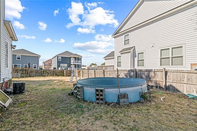 view of yard featuring central AC unit, a swimming pool, and a fenced backyard