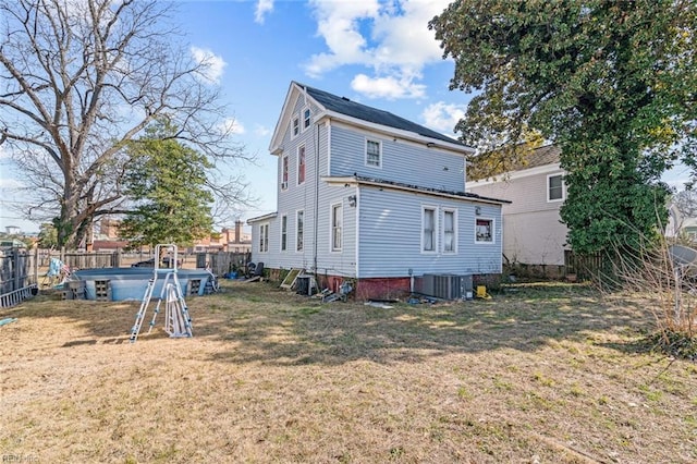 back of house featuring central air condition unit, a fenced backyard, a swimming pool, and a lawn