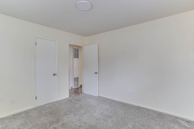 carpeted empty room featuring visible vents and baseboards