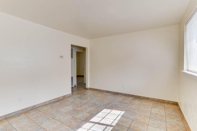 spare room with baseboards and light tile patterned floors