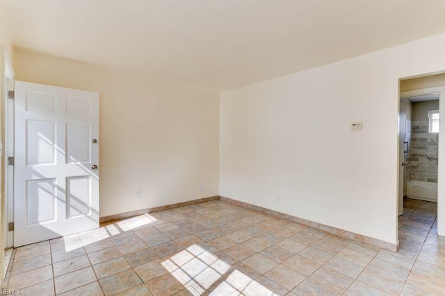 empty room featuring light tile patterned flooring and baseboards