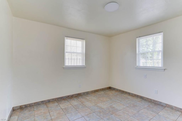 spare room with baseboards and a healthy amount of sunlight