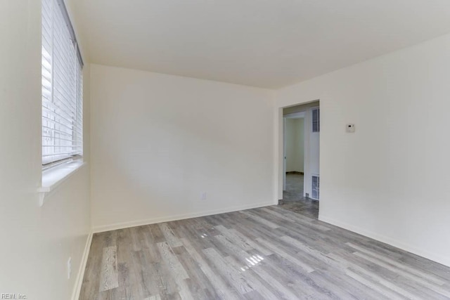 spare room with visible vents, baseboards, and wood finished floors