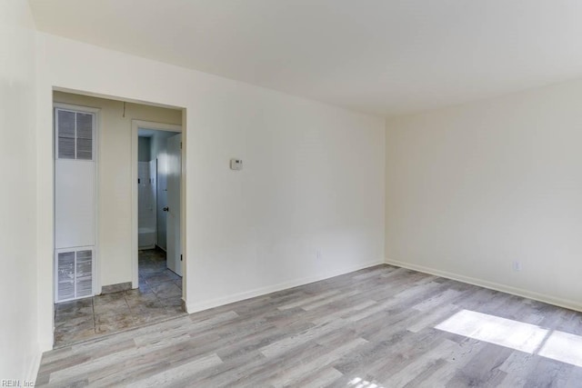 unfurnished room featuring visible vents, baseboards, and wood finished floors