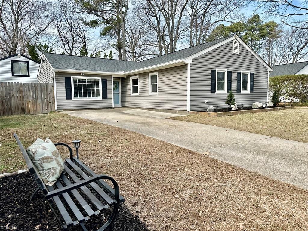 ranch-style home featuring roof with shingles, fence, and driveway