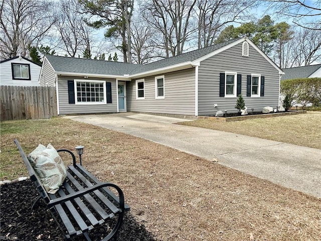 ranch-style home featuring roof with shingles, fence, and driveway