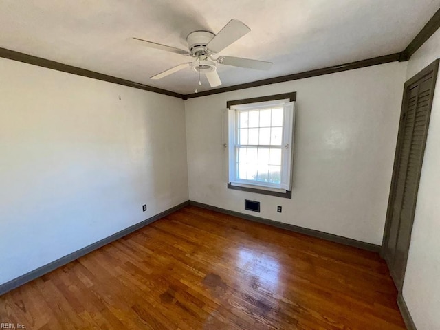 spare room with baseboards, wood finished floors, and crown molding