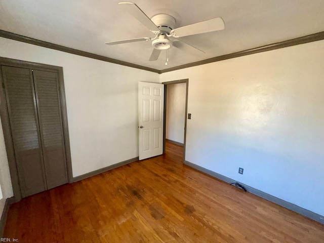 unfurnished bedroom featuring crown molding, baseboards, and wood finished floors