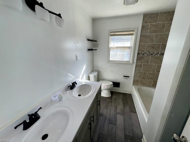 bathroom featuring a bathtub, a sink, toilet, and wood finished floors