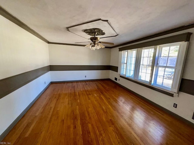 empty room with baseboards, wood finished floors, a ceiling fan, and crown molding