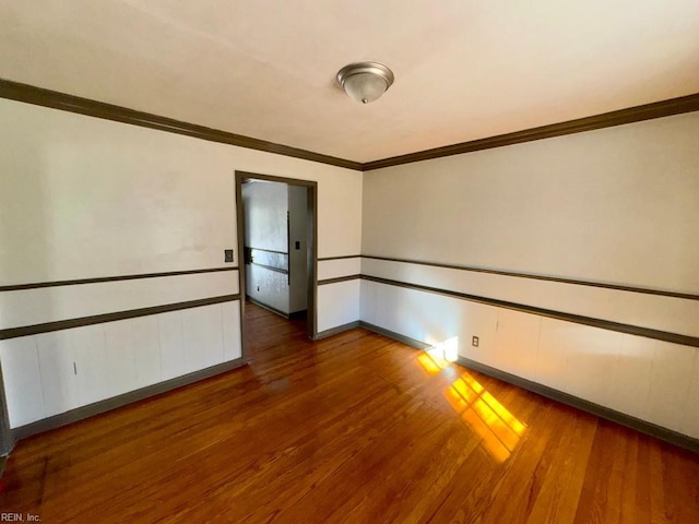 unfurnished room with baseboards, ornamental molding, and wood finished floors