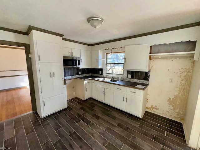 kitchen with white cabinetry, stainless steel microwave, a sink, and wood finish floors