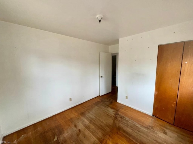 unfurnished bedroom featuring a closet, baseboards, and wood finished floors