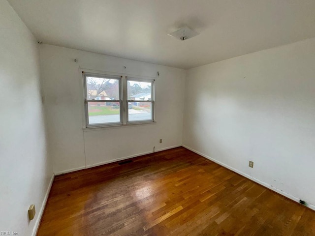 spare room featuring baseboards and wood finished floors