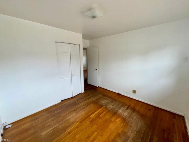 unfurnished bedroom with a closet, baseboards, and wood finished floors