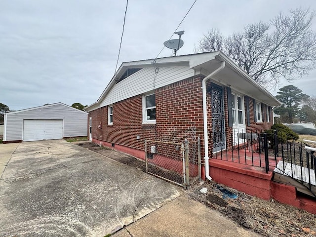 view of side of home with a garage, driveway, brick siding, and an outdoor structure