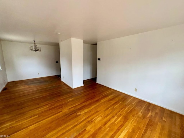 spare room featuring a notable chandelier and wood finished floors