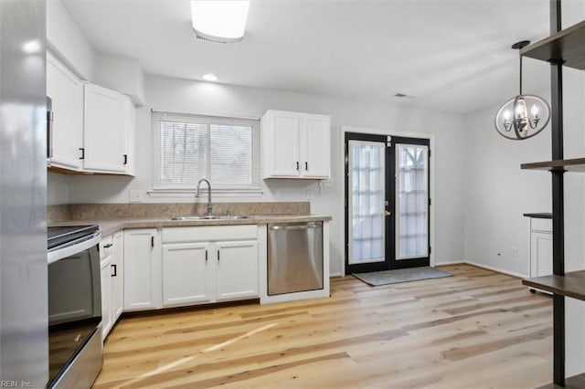 kitchen with appliances with stainless steel finishes, a sink, white cabinetry, and a healthy amount of sunlight