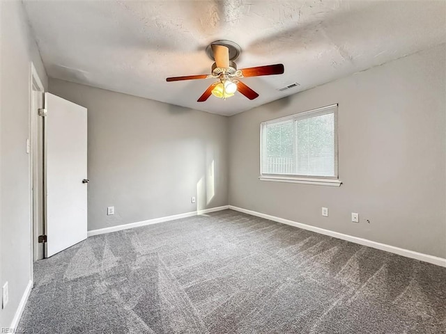 spare room with carpet floors, visible vents, baseboards, and a ceiling fan