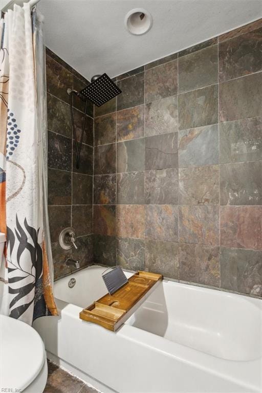 bathroom featuring shower / bathtub combination with curtain and toilet