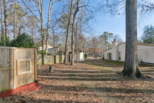 view of yard with an outbuilding, a storage shed, and fence