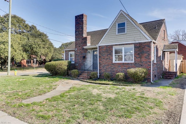 view of front of home featuring a chimney, a front lawn, and brick siding