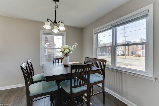 dining area featuring a chandelier, dark wood finished floors, and baseboards