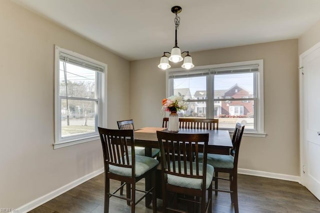 dining area featuring an inviting chandelier, baseboards, and dark wood finished floors