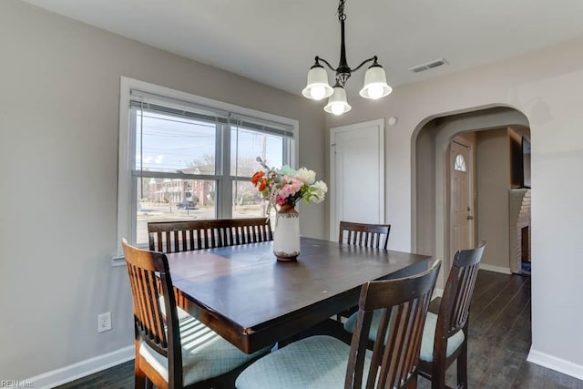 dining space featuring arched walkways, dark wood finished floors, visible vents, an inviting chandelier, and baseboards