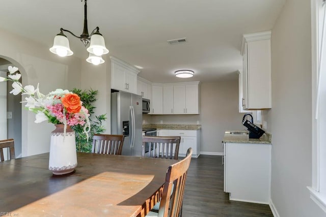 dining space featuring baseboards, visible vents, arched walkways, and dark wood-type flooring