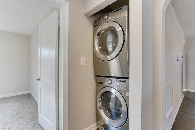 laundry area with laundry area, carpet, stacked washer and clothes dryer, and baseboards