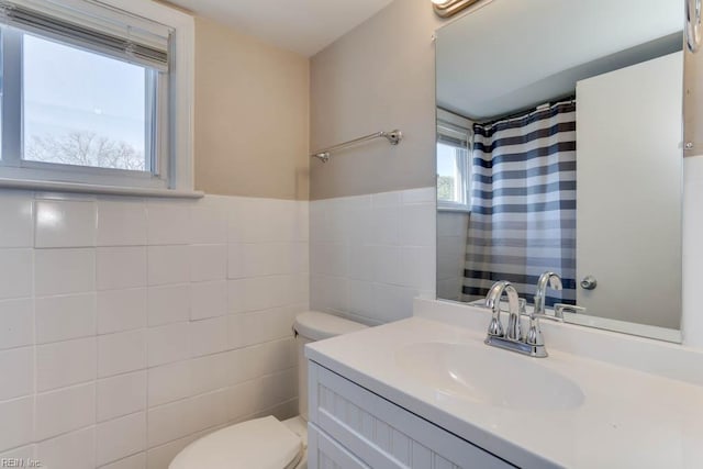 bathroom with curtained shower, toilet, a wainscoted wall, vanity, and tile walls